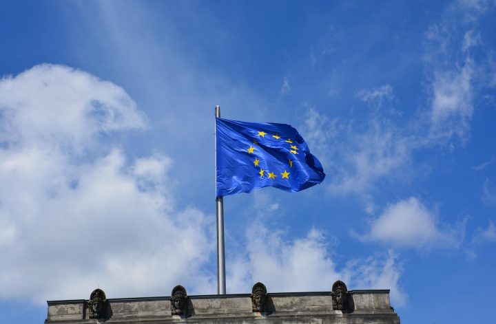 Flaga Unii Europejskiej powiewająca na tle błękitnego nieba symbolizuje dotacje unijne.